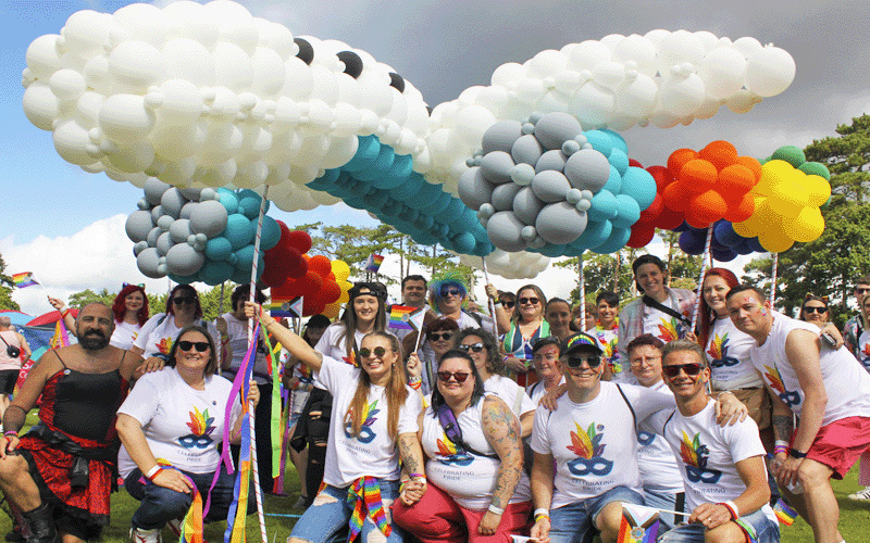 a group photo of Gatwick colleagues at Crawley Pride holding a large airplane made of balloons